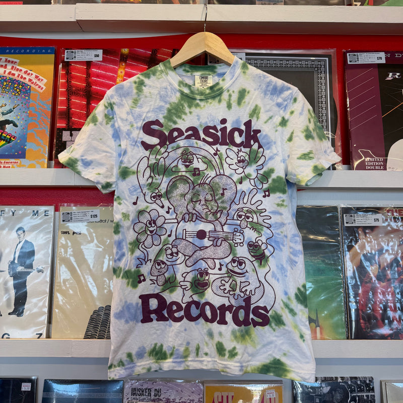 Tie-dye t-shirt with 'Seasick Records' design hanging in front of record album covers.